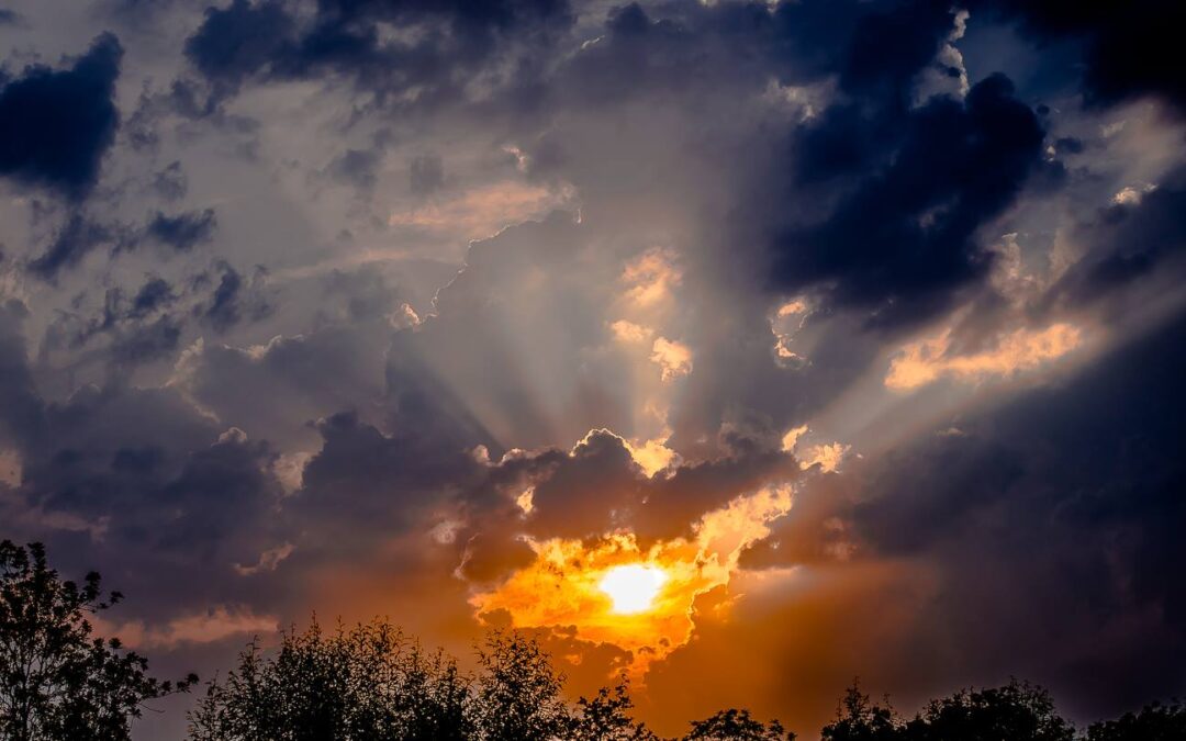 Fel oranje ondergaande zon met donkere wolken eromheen