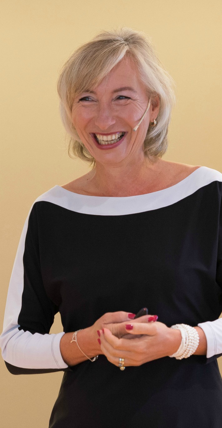 Linda Spaanbroek lachende vrouw met grijs haar in een zwarte jurk met een witte streep aan de hals