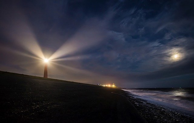 Vuurtoren schijnt licht op zee in een donkere nacht
