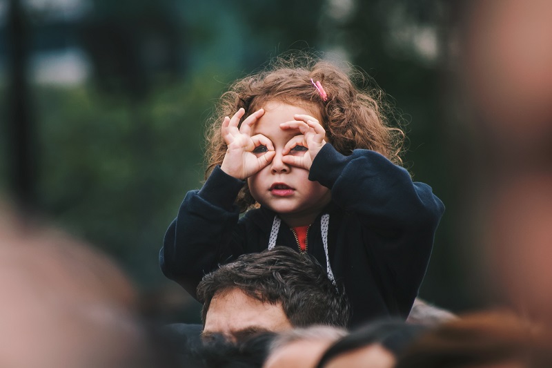 Meisje op schouders van vader vingers om ogen doorzien