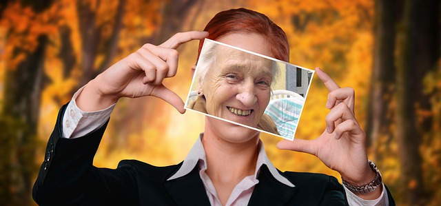 Jonge vrouw met foto van oude vrouw voor haar gezicht menopauze