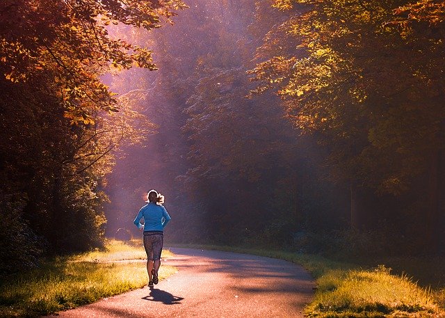 Vrouw loopt hard op een geasfalteerde weg in het bos