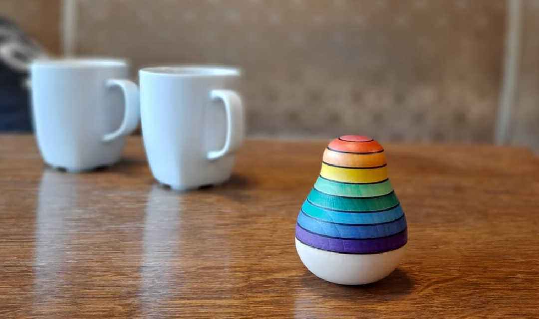 regenboogpopje & koffie marmeren tafel waaraan twee mensen koffie drinken met de tekst stay in touch regelmatige begeleiding